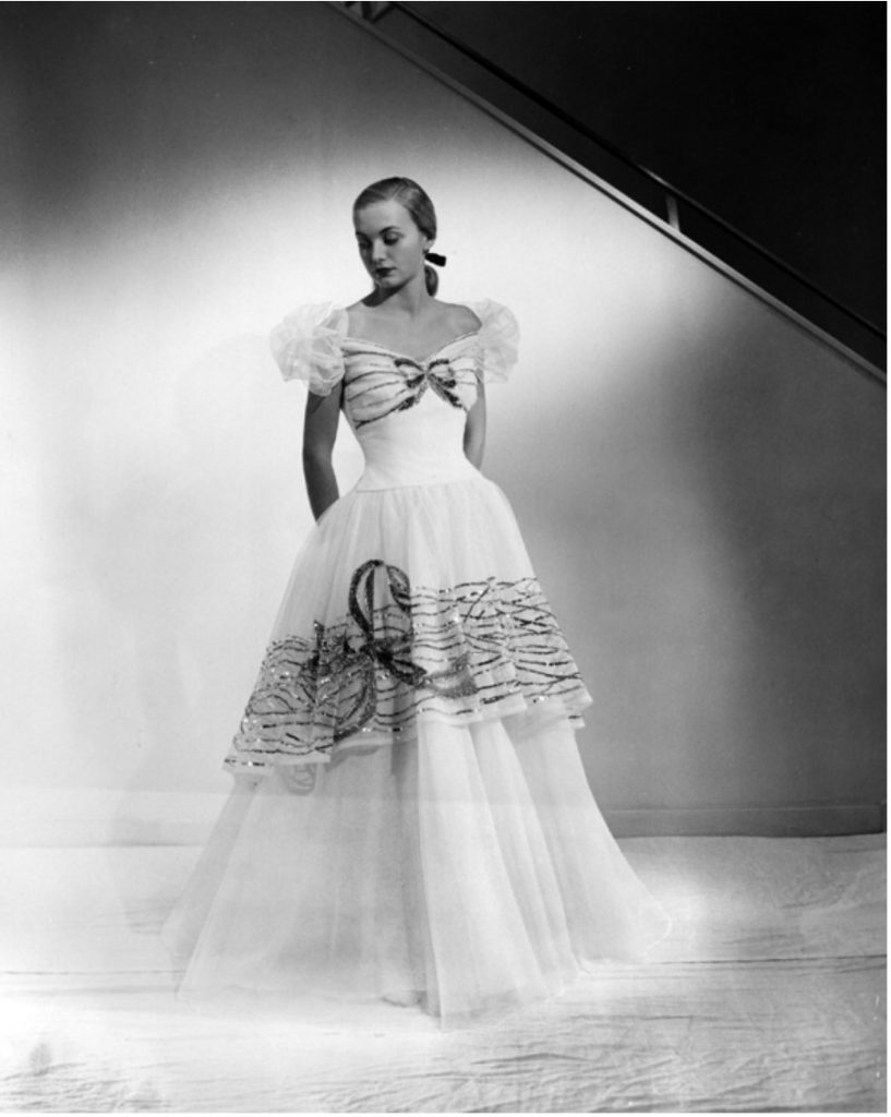 1940s Vintage Photo of a model in a 1947 Emma Domb Evening Gown. A debutante’s dream gown that will make its bow in Paris on October 16 – Emma Domb’s bouffant white net frock designed for dancing. Created for San Francisco’s “Fashion Premiere in Paris” on October 16