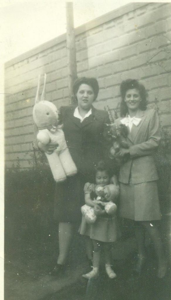 1940s vintage photo of Easter 1945 featuring two women in 1940's skirt suits holding a giant easter bunny stuffed animal and a little girl holding a stuffed toy. Super 1940s Hairstyles.