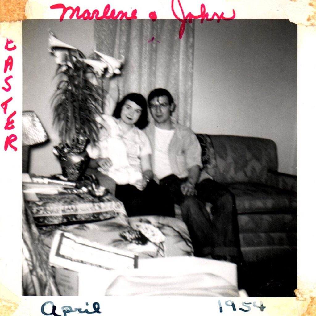 1950s vintage photo of a 1950s couple celebrating Easter with a easter lily and stuffed easter bunny in the photo. 