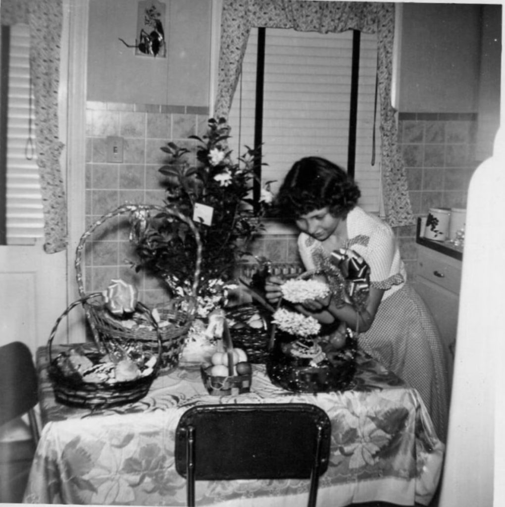 1950s vintage photo of a young woman filling easter baskets on her kitchen table.