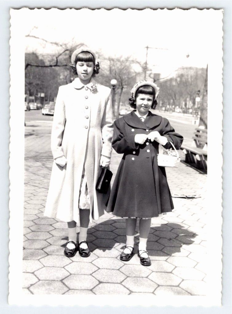 1950s vintage photo of two girls at Easter time in their Easter clothes and easter hats holding easter basket