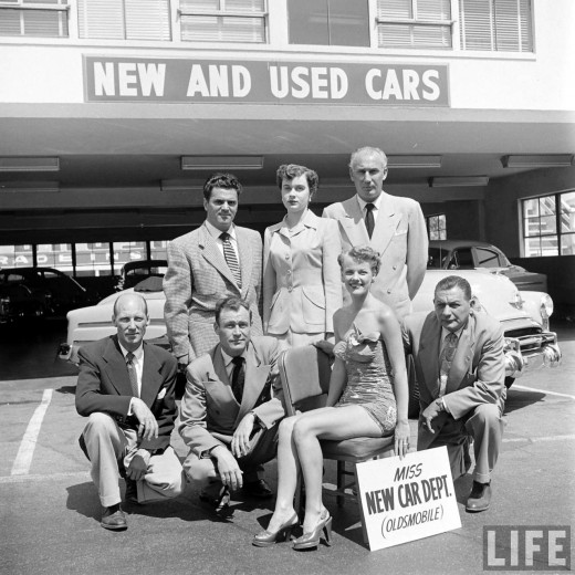 1950s vintage photo from 1951 of a beauty pageant featuring a woman in a 1950s swimsuit representing "Miss New Car" of the Muller bros dealership.