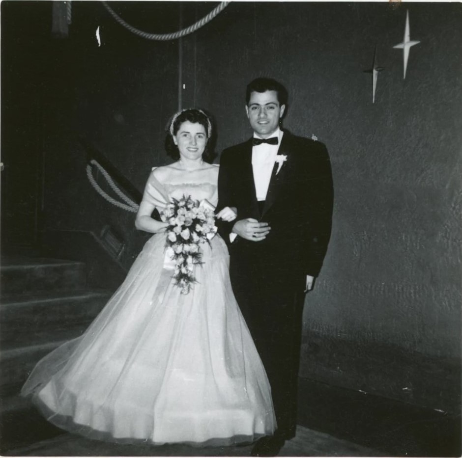 1950s vintage wedding photo of a bride in her 1950s wedding dress posing with her groom in his 1950s tuxedo with starburst designs on the wall.