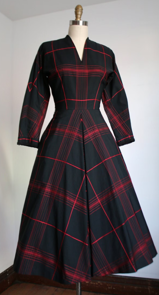 1950s Fashion: Beautiful black with red dress from the 1950s from fashion brand L'Aiglon. This dress features a structured bodice, fitted waistline, longer sleeves, and a full skirt. Metal zipper.
