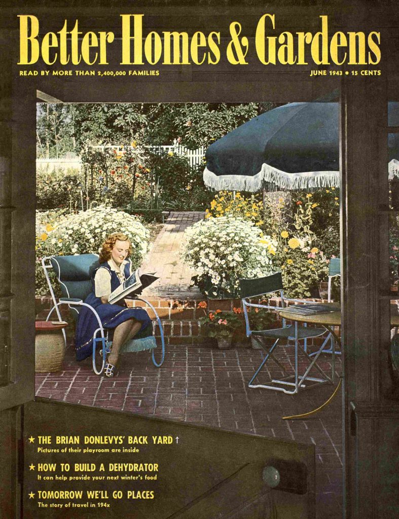 1940s vintage magazine cover from June 1943 featuring on the cover a women enjoying her floral garden while sitting on her backyard patio furniture including a fridged umbrella. 