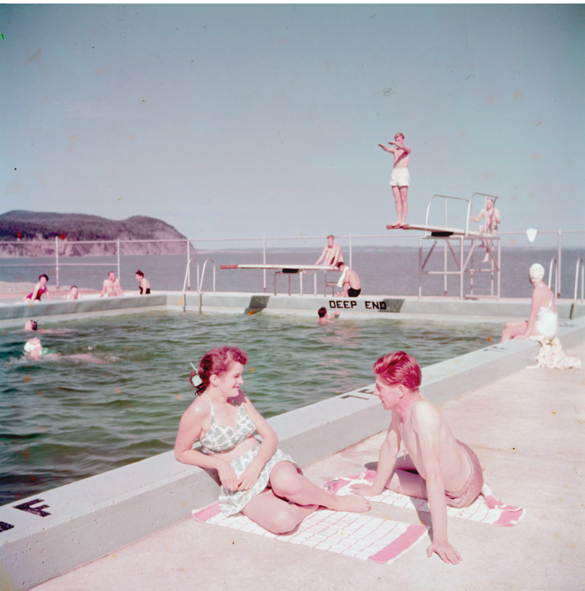 1950s vintage photo of a young couple in 1950s swimsuits hanging out beside a swimming pool at the Fundy National Park Swimming pool, New Brunswick