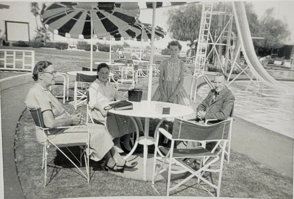 1950s Vintage photo taken poolside at the Shadow Mountain Club in Palm Springs, 1957. featuring 2 young girls and and older couple sitting around a table.