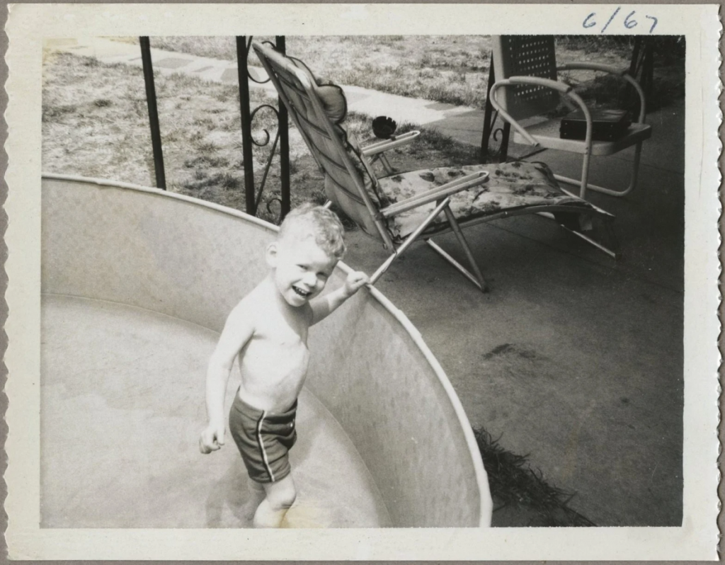 1960s vintage photo june 1967 of a young boy in a portable swimming pool with 1960s mid century patio furniture beside the pool