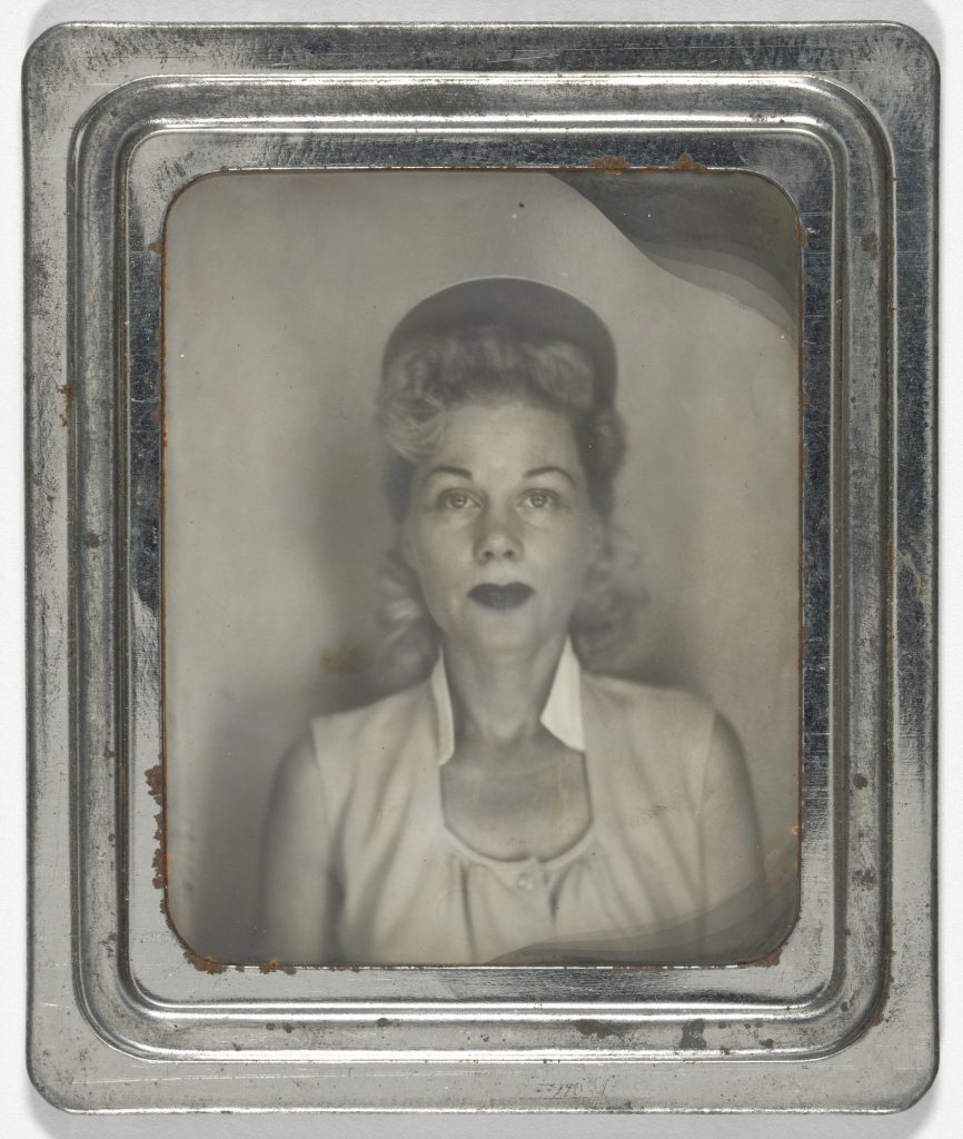 1940s vintage photo booth image of a woman with red lips and baseball hat. She looks like a baseball player from a League of their Own