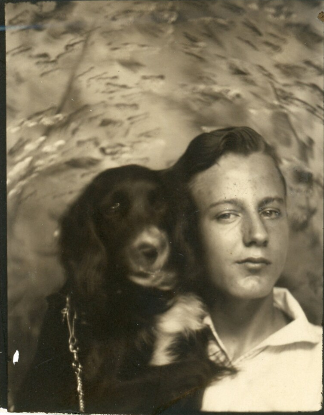 1940s vintage photo booth image of a young man posing with his cocker spaniel dog. 