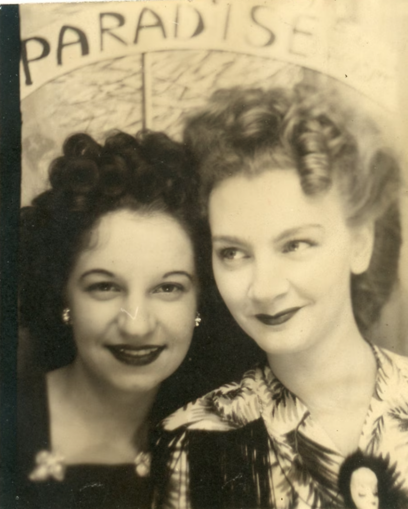 1940s vintage photo booth image of two women with curly 1940s hairstyles and dress clips and brooches posing together