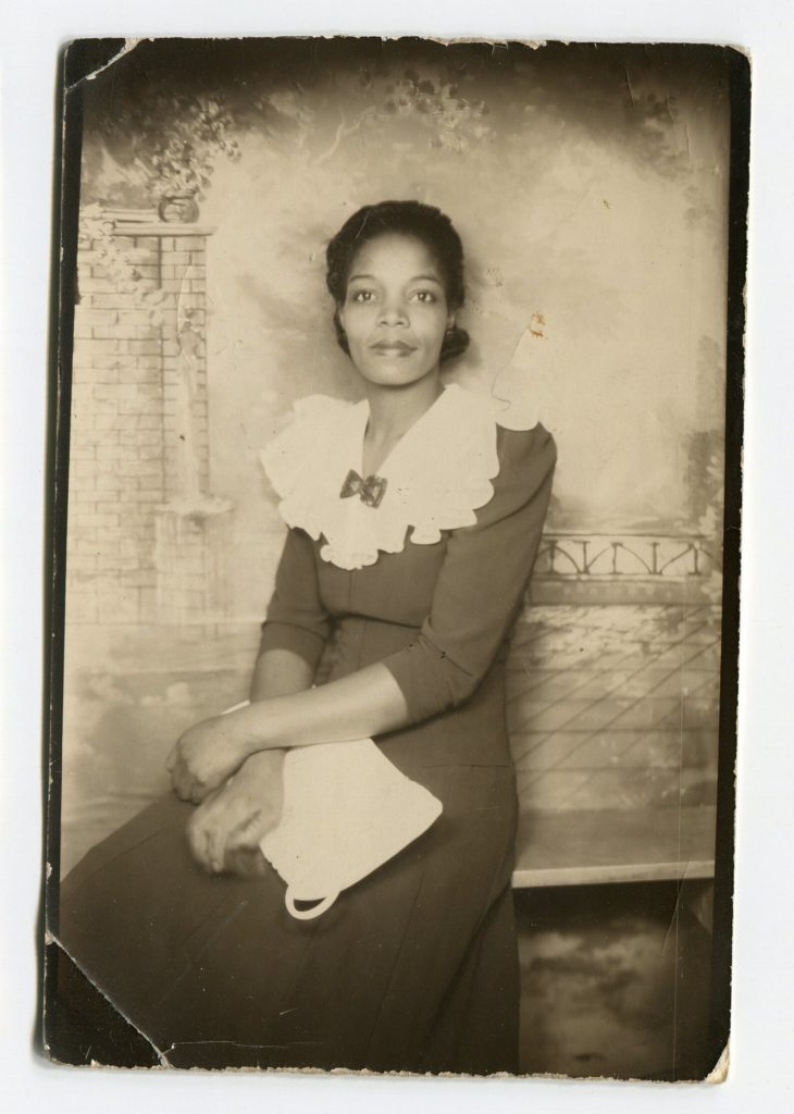 1940s vintage photo booth image of a pretty Black woman in a 1940's dress posing for a photo. 