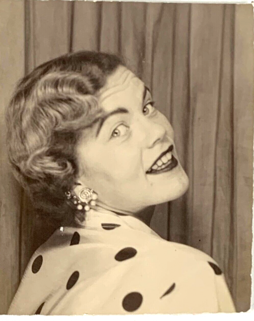 1950s vintage photo booth image of a young woman in a polkdot shirt and clip on earrings posing sexy.