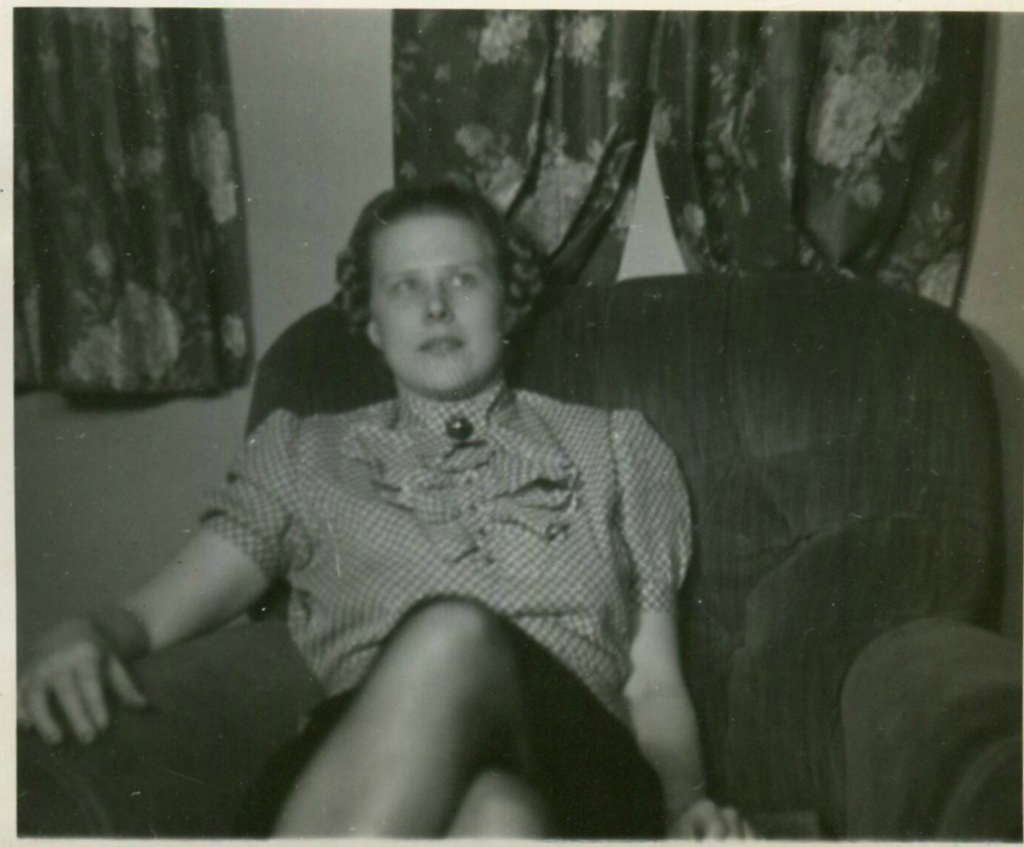 1930s vintage photo of a young woman with braids in her hair and 1930s top sitting in an large armchair