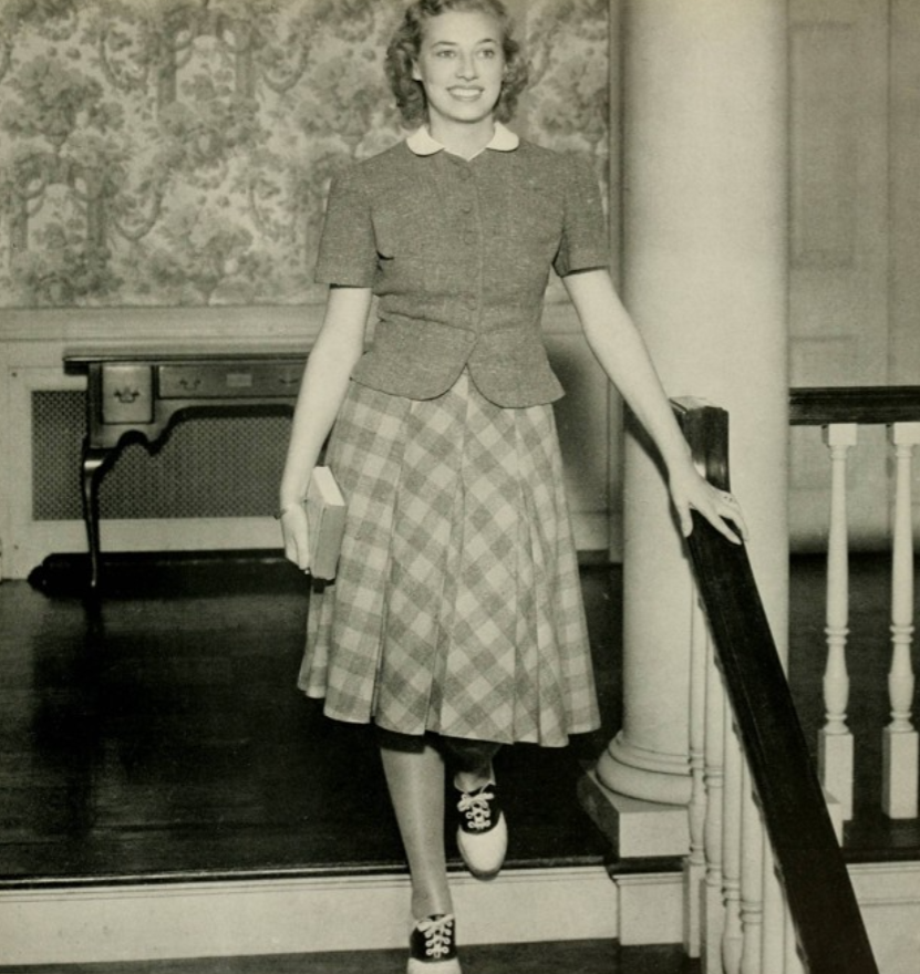 1940s vintage photo: 1941 yearbook photo from the Woman’s College of the University of North Carolina of a young woman wearing saddle shoes walking down the stairs of her school.