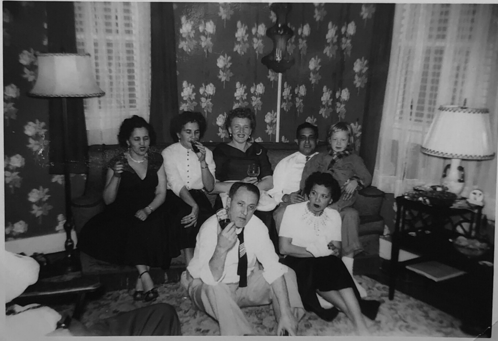 1940s vintage photo of a group photo taken in the living room on a couch and floor during a party. 