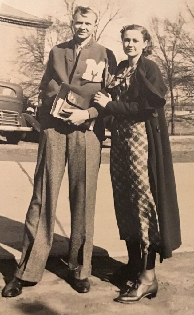 1930s Photo from 1936 of a young man wearing a Millsaps Majors Letterman Jacket (Varsity jacket) - Jackson Mississippi posing with his stylish girlfriend / wife in a plaid 1930s dress and long coat. 