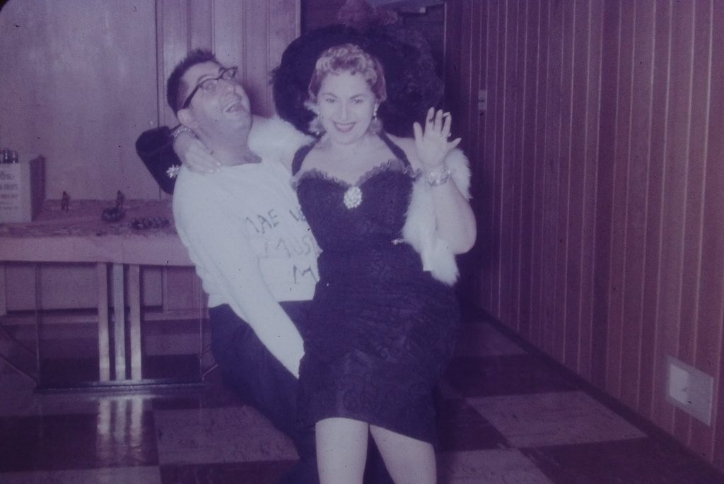 1960s vintage halloween photo from an adult halloween party in 1967. The couple is dressed up as Mae West and her fan.