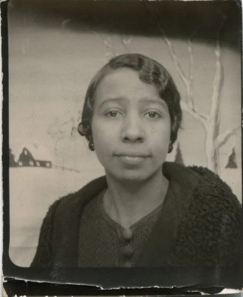 1920s /1930s vintage photo of a young Black woman posing in a photobooth in front of a winter landscape. 