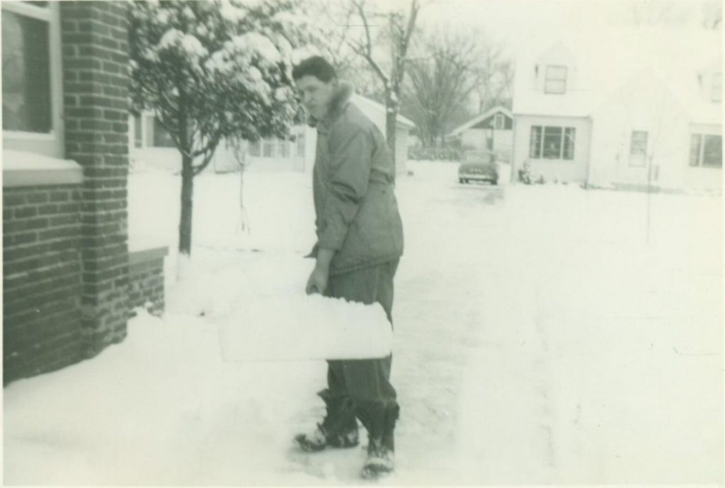 1940s vintage photo of an Unhappy Man Shoveling Snow in his drivewary after a snowstorm. 