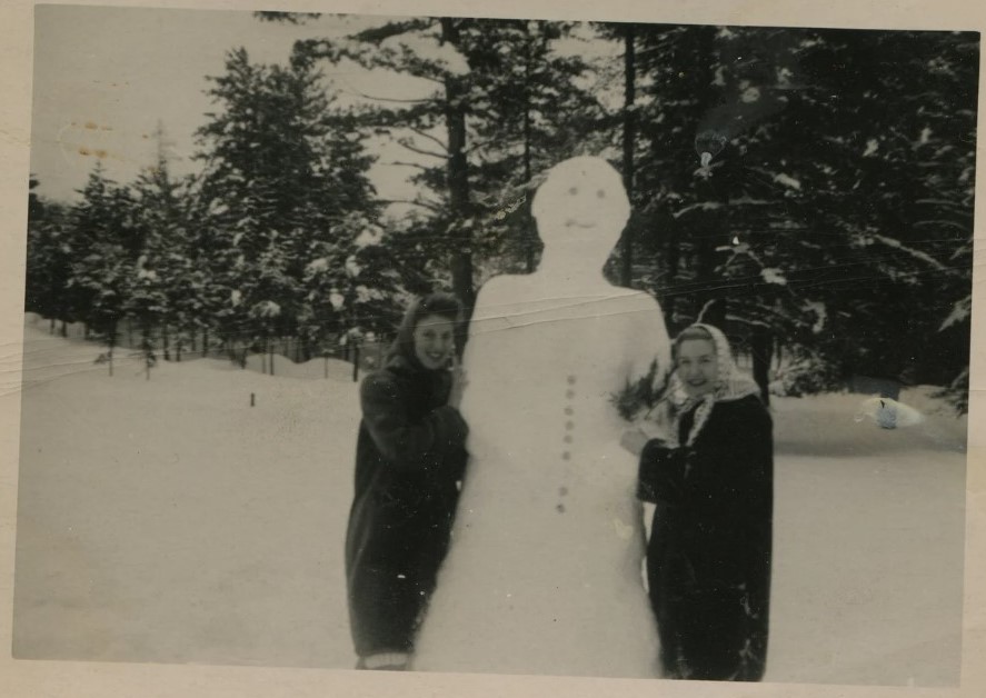 1940s vintage photo of two women posing with a giant tall snowman they built.