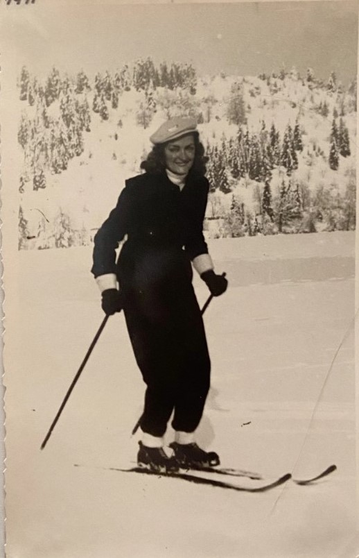 1940s vintage photo of a woman skiing and posing for a photo outside in her ski suit