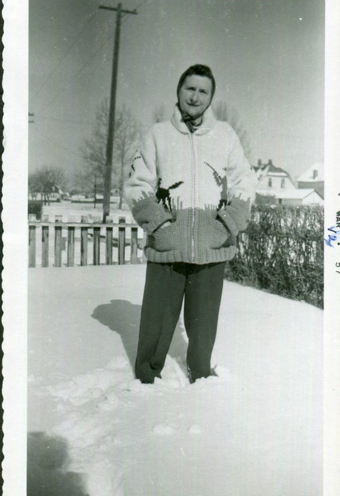 March 1957-1950s vintage photo of a woman posing in the snow in a hand knitted sweater.