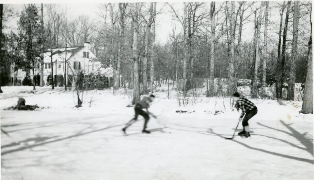 1950s vintage photo of two boys playing hockey on a pond outside during the winter time