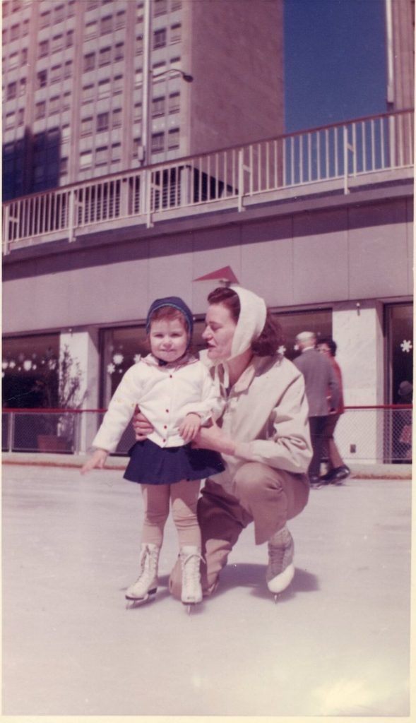 1960s vintage photo of a young girl and her mother ice skating at an outdoor ice rink.