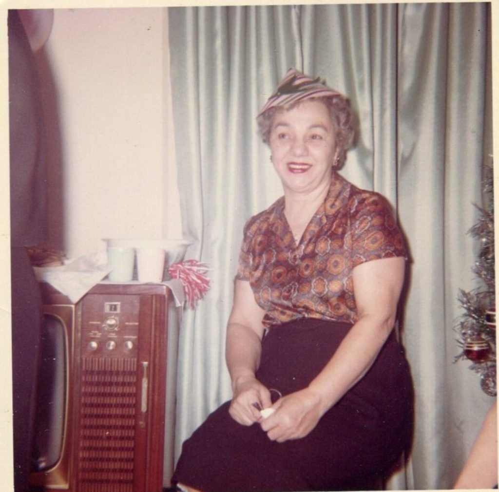 1950s 1960s vintage photo of a woman wearing a party hat on New Years eve posing by the christmas tree