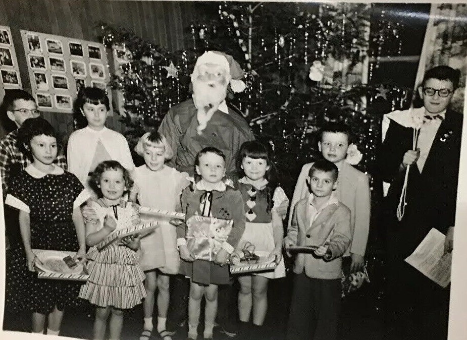 1950s/1960s kids Christmas party vintage photo featuring a person dressed up as Santa with a mask on. 