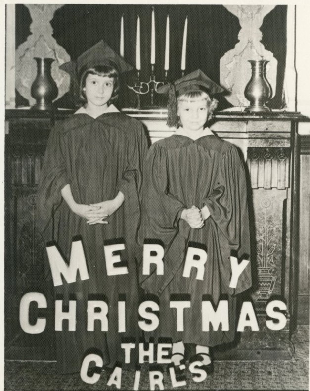 1950s vintage christmas card featuring a photo of two young girls in graduation gowns