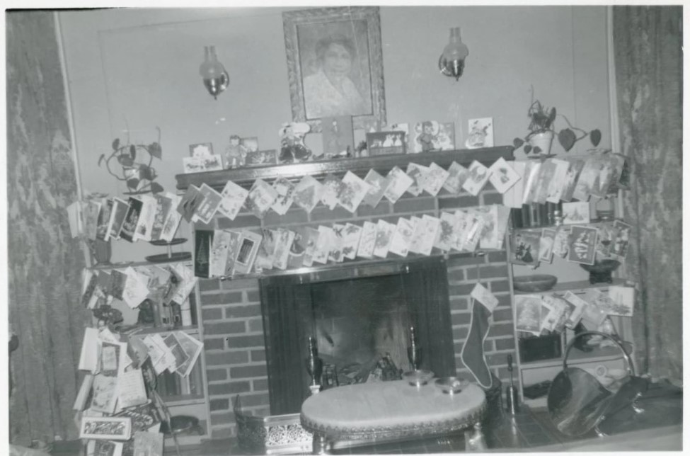 1950s vintage photo of a fireplace mantel with christmas cards all around it and a stocking hung with care