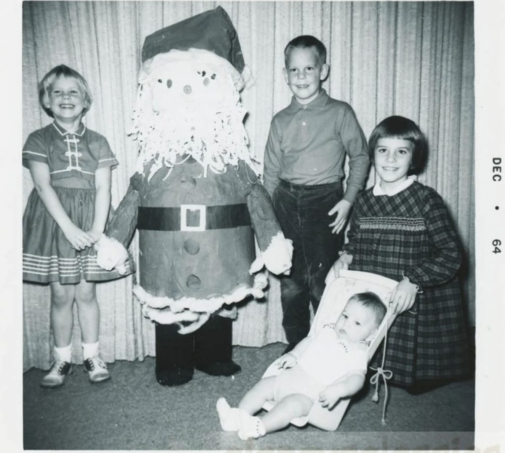 1960s vintage photo from Dec 1964 of 4 young kids posing with a paper mache Santa Claus