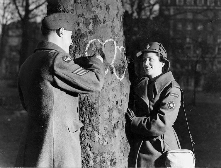 1940s vintage photo Canadian Women's Army Corps (CWAC) Valentine's Day 1944 -Young military couple chalking hearts onto a tree during WW2. 