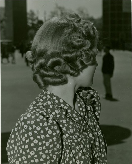 1940s vintage photo: A woman in 1940 at the New York World's Fair at the 'World of Fashion' Exhibit showing off a 1940 hairstyle (the back) with beautiful sculptured curls. Super early 1940s hairstyle inspiration.