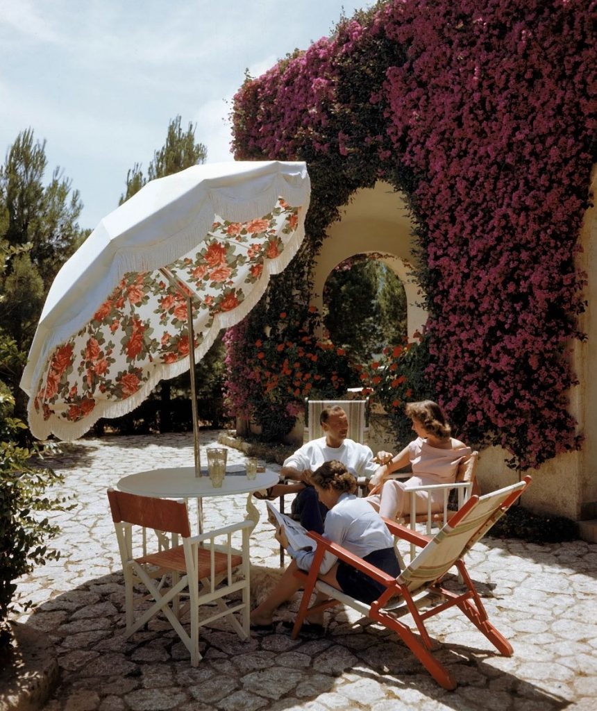 1940s vintage photo of a 3 people sitting in a garden by a large patio umbrella in Capri Italy in 1949. Vintage Vacation Photo