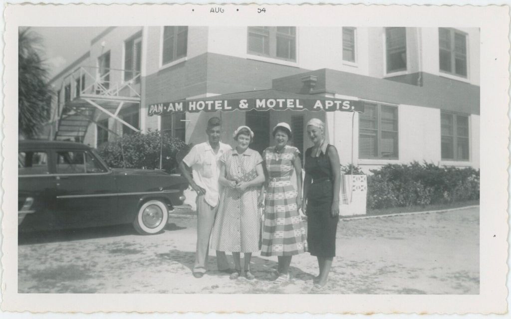 1950s photo: Fun vacation photo from August 1954 of a group of people posing in front of the Pan-Am Hotel & Motel Apts. Super 1950s fashions.