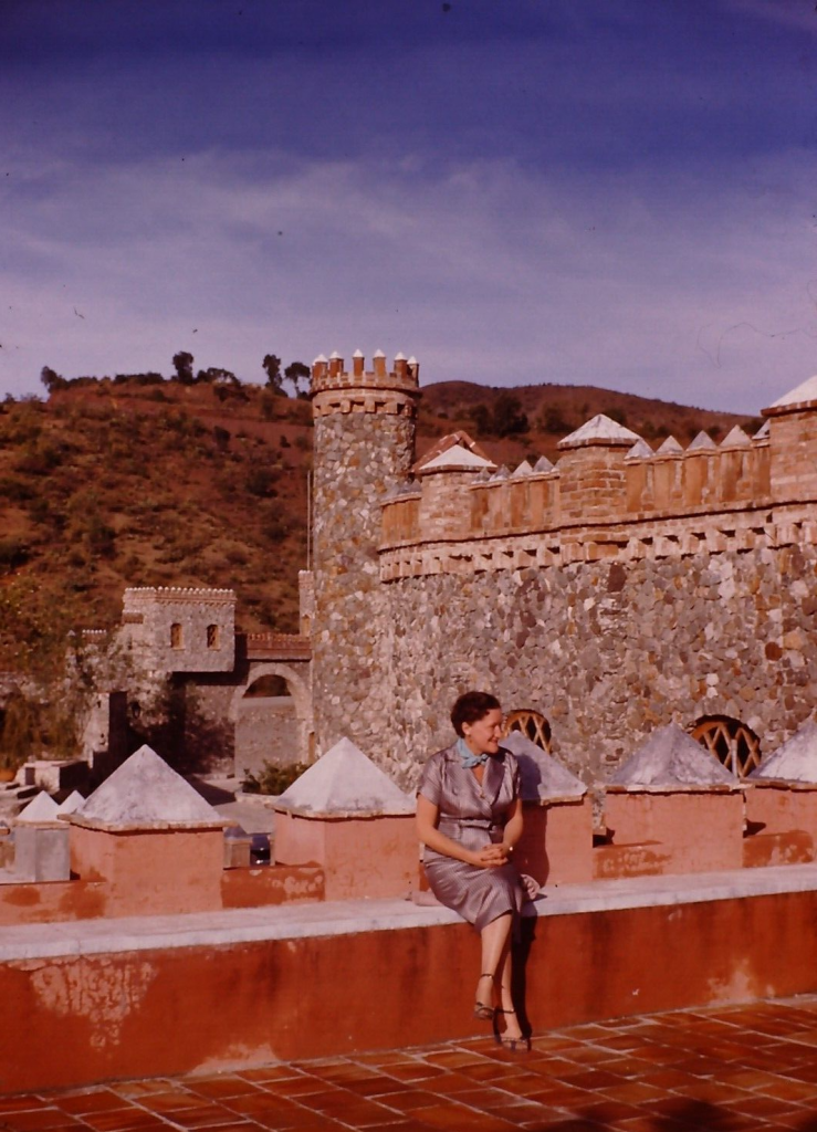 1950s Vacation Photo: 1954 Guanajuato Mexico. A woman in an pretty 1950s dress poses casually on a wall.