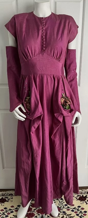 1940s Fashion: A Fred Perlberg 1940s dark mauve moire taffeta dress. The dress is unique, featuring side bustles with faux flower bouquet and rhinestone embellishments. The dress also has matching, open arm band gloves.