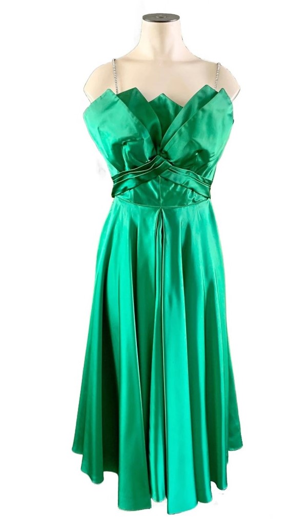 1950s or 1960s emerald green satin fabric with a fitted bodice and full skirt, Fred Perlberg dress. Bodice is completely boned for support and ends in petal-like points of fabric at bust.