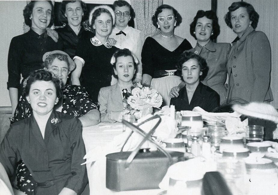 1950s vintage photo of a 1953 bridal shower featuring a group of women including the bride to be in 1950s fashions, 1950s dresses, cat eye glasses, 1950s hairstyles and 1950s hats