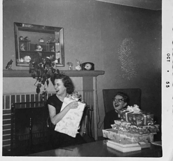 October 1955 Bridal Shower vintage photo. The 1950s vintage image features a laughing bride to be opening up her gifts with a fantastic 1950s shadow box above the mantel.