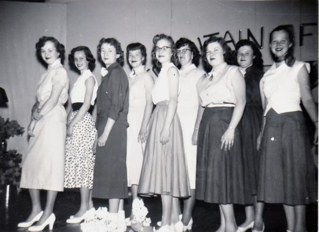 1950s vintage photo of Teenage girls at a fashion show. They are all wearing 1950s fashions and 1950s hairstyles. 