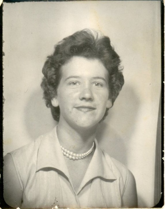 1950s vintage photo of a young woman wearing a 1950s hairstyle and a parl necklace. No makeup. 