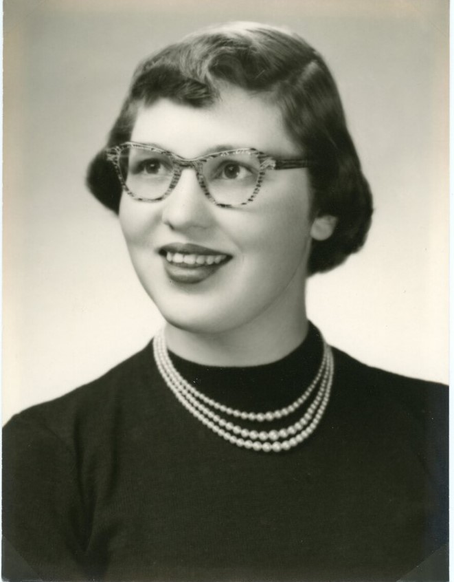 1950s vintage photo of a young woman with red lips, short 1950s hairstyle and 1950s eyeglasses on with pearls around her neck