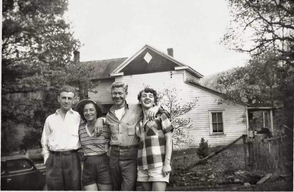 1950s vintage photo of a 2 couples or friends posing in front of a house. The women are wearing shorts and casual tops. Fun 1950s fashion inspiration.