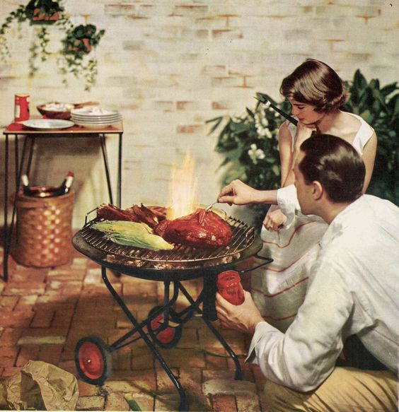 1950s vintage photo of a couple having a barbeque on their patio in 1958 in their 1950s fashions. 