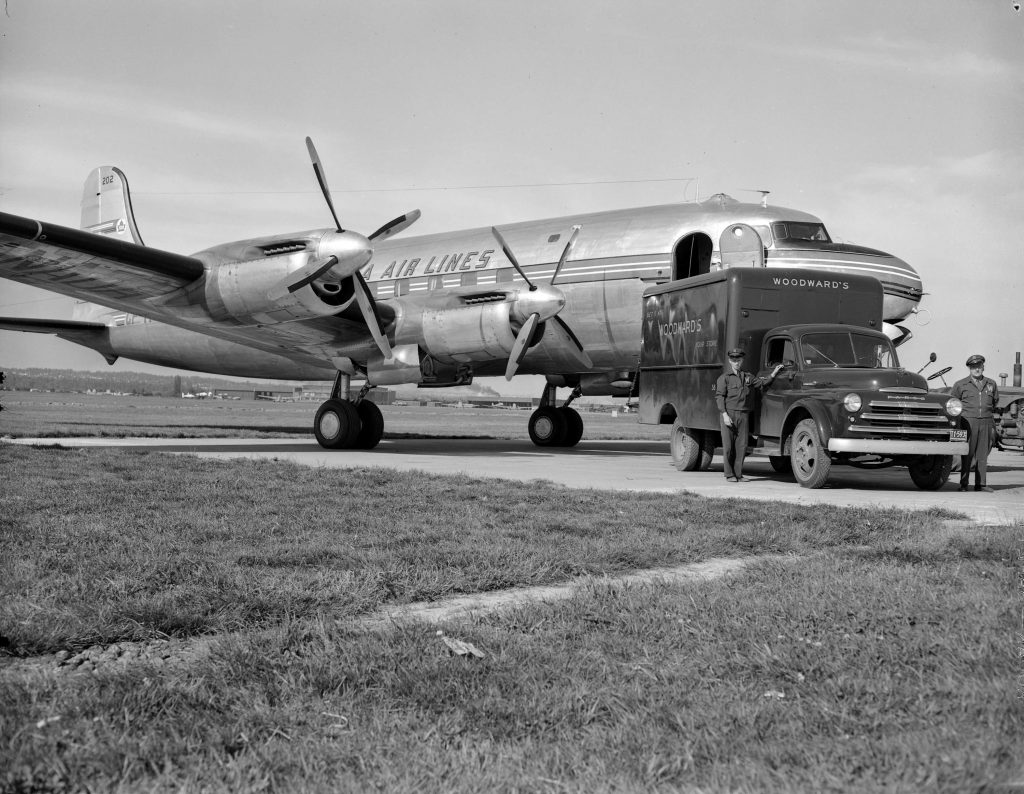 1940s vintage photo from 1948 of a Woodward's department store truck parked by a Trans-Canada Air Lines plane at the airport