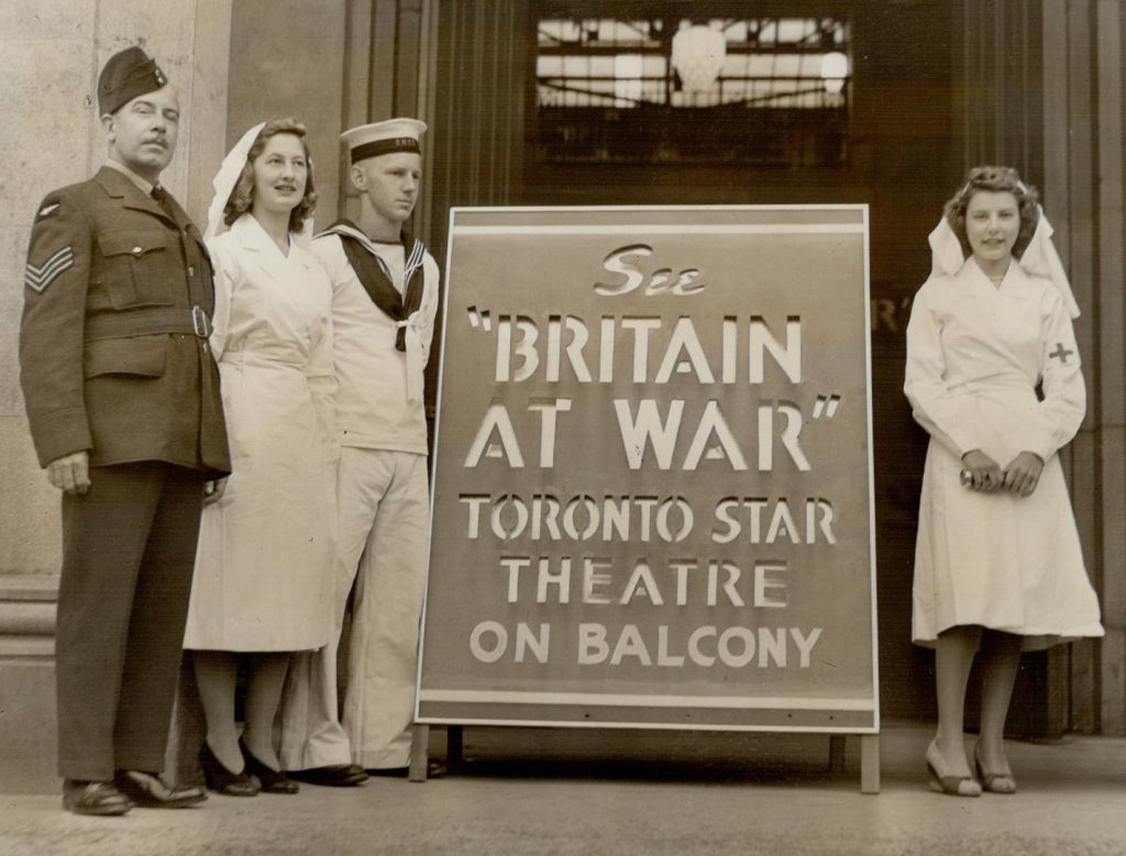 1940s vintage photo: 1941 photo: C.N.E. crowds see first showing of 'Britain at War' in Toronto (Canadian National Exhibition). The image features 2 women in nurses uniforms and 2 men in uniforms. 